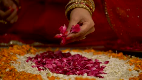 diwali decoration - indian women making flower rangoli with rose petals