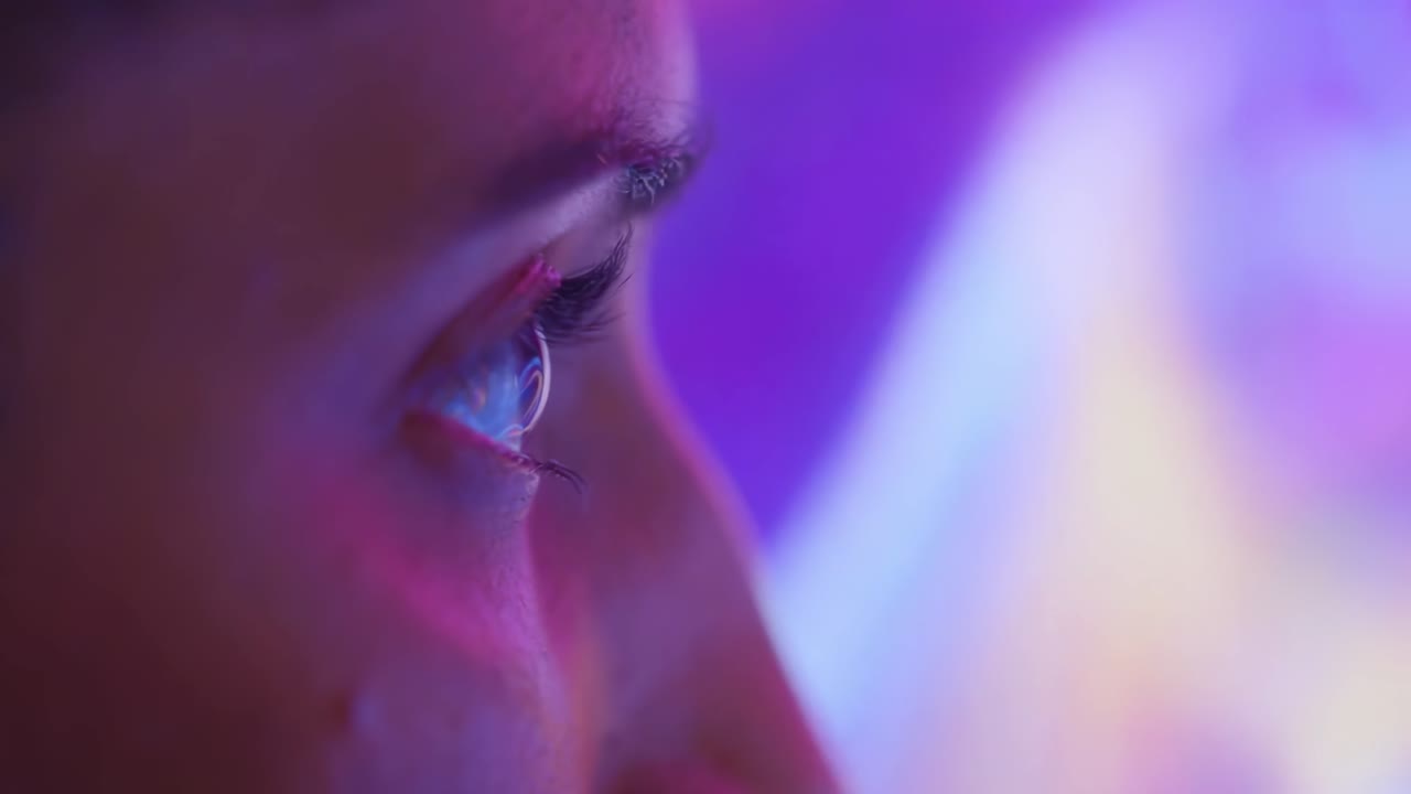 Side profile of a woman gazing at a vibrant digital screen, shot at eye level
