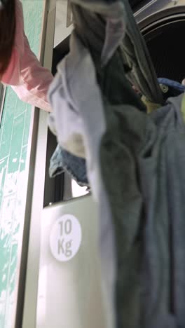 person loading clothes into a self-service washing machine