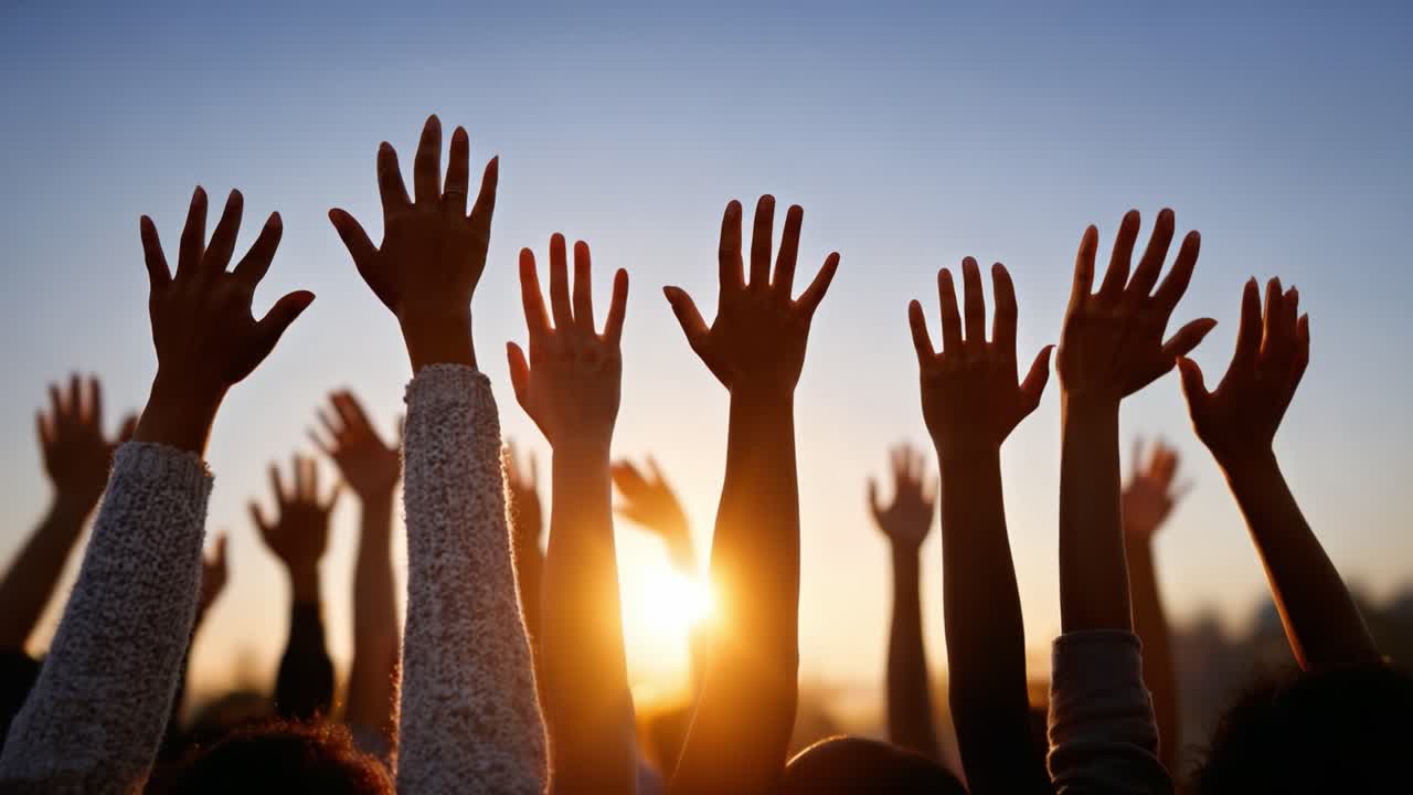 A sea of hands reaches toward the sky during a breathtaking sunset, symbolizing unity, hope, and collective aspiration as the day comes to a close