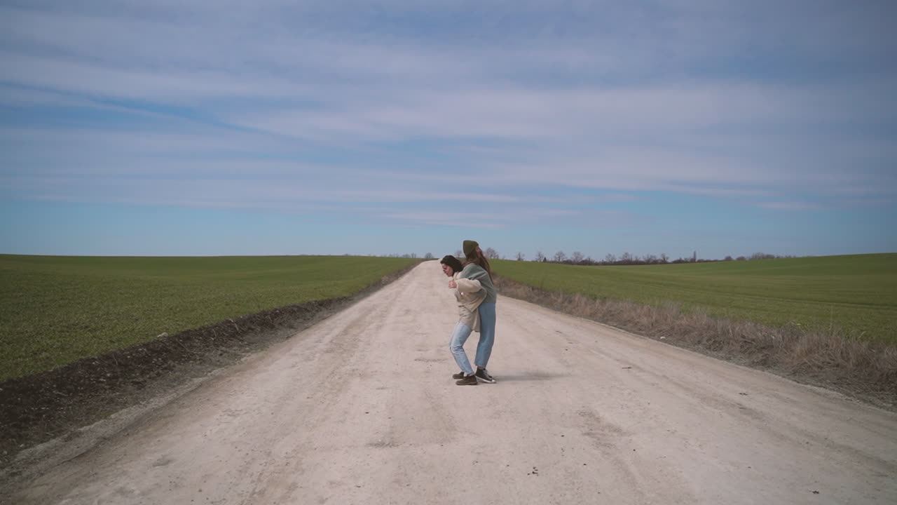 dos chicas jóvenes jugando teeter totter en medio de un camino perdido en el campo