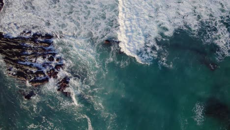 waves break on rocky coastline, top down aearial drone, abstract view