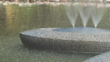 view on water splashing from isolated fountain “sun boats” in jaunpilsētas square in ventspils in sunny summer day, closeup shot