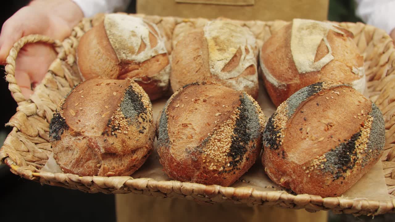 The baker holds in hands a of fresh bread with black poppy garnish on top close-up. Artisan bread is making by skill bakers using natural and high-quality ingredients. Food with health and flavour benefits.