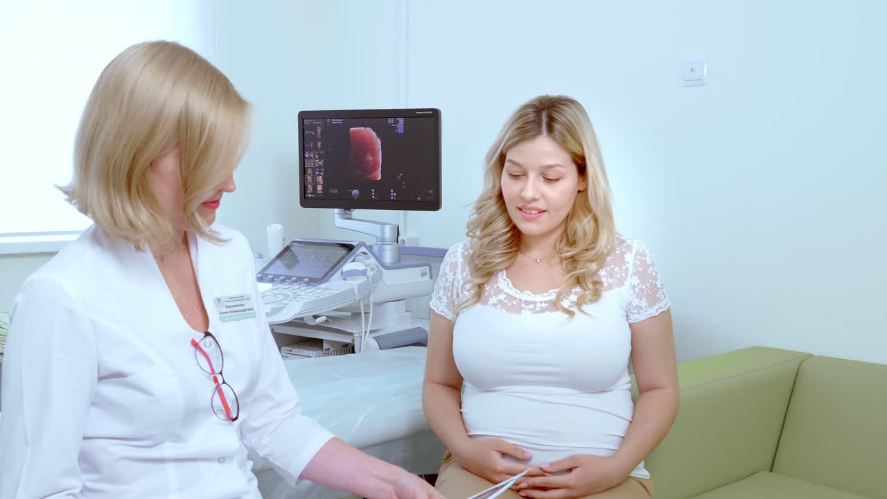 Doctor consults with pregnant patient during ultrasound scan