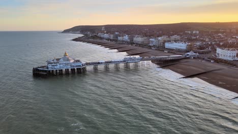 Eastbourne-Pier-Y-La-Ciudad-Al-Atardecer-Sussex-Uk-Antena-Retroceder-Revelar-Vista-4k