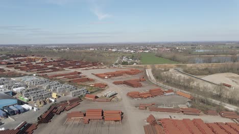 Flying-past-old-smoke-stack-overlooking-large-industrial-junk-yard