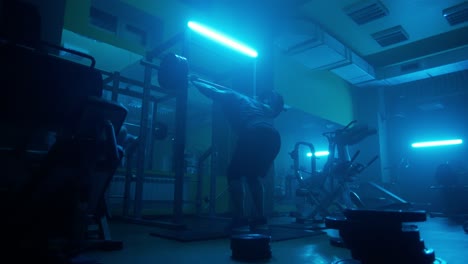 man weightlifting in a gym under blue light