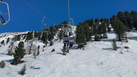 pov on 2-person chairlift up sunny mountain snow ski slope in trees