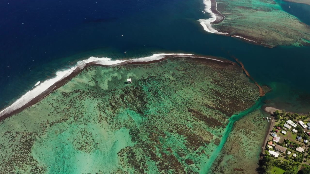 Un drone aereo scivola lungo il passaggio della barriera corallina di Teahupoo, Tahiti, dove le acque basse turchesi precipitano improvvisamente nell'oceano Pacifico aperto e di un blu profondo