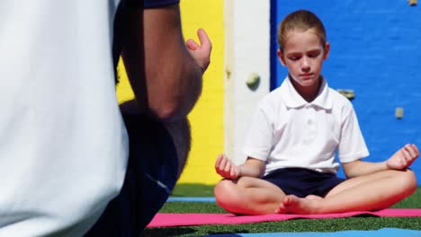 yoga instructor instructing children in performing yoga