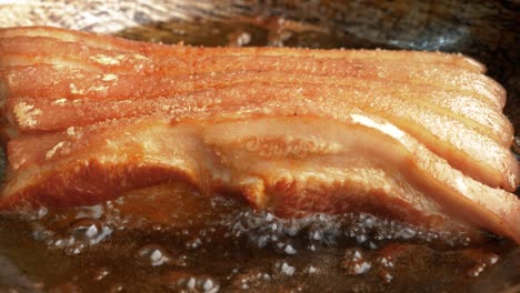 zoom in shot of pork belly deep frying in hot oil, traditional meal