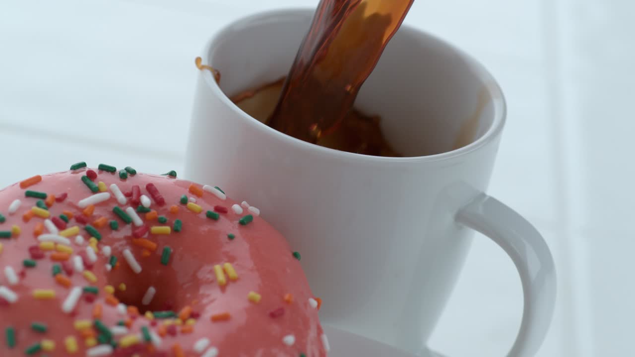 Ciambella con caffè che si versa al rallentatore