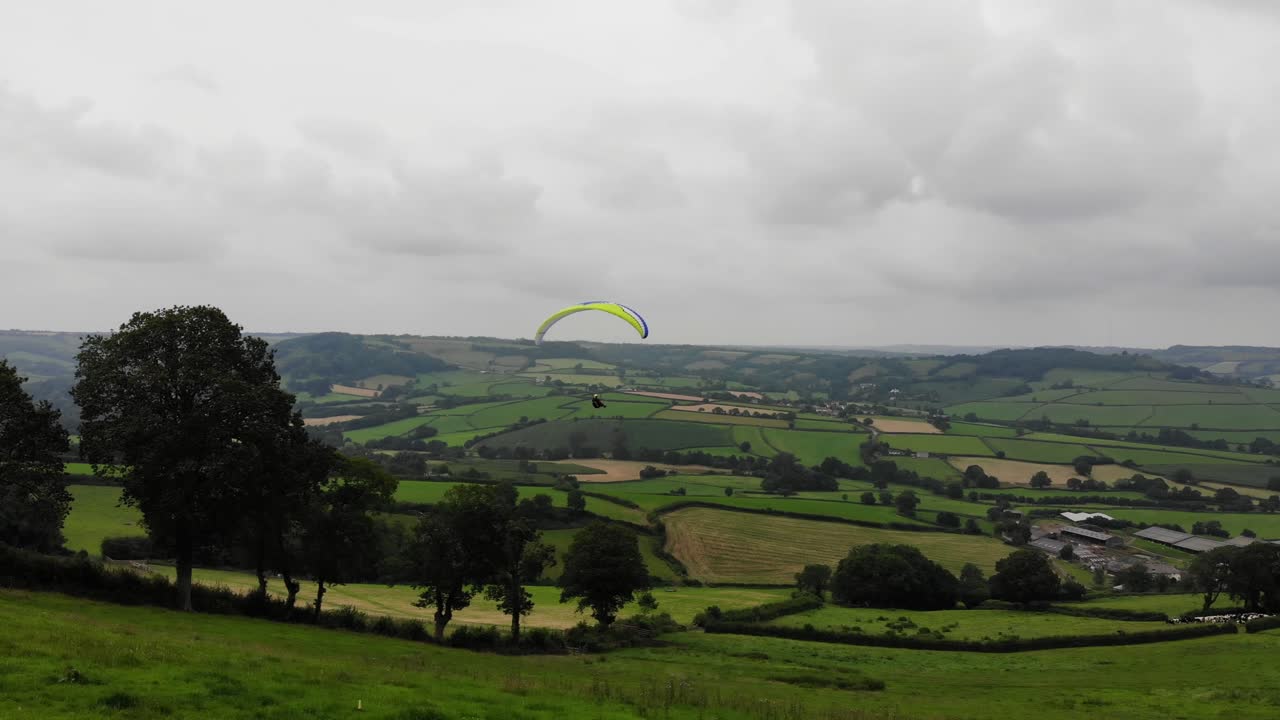 disparo hacia adelante siguiendo un parapente que surca el cielo sobre la campiña inglesa