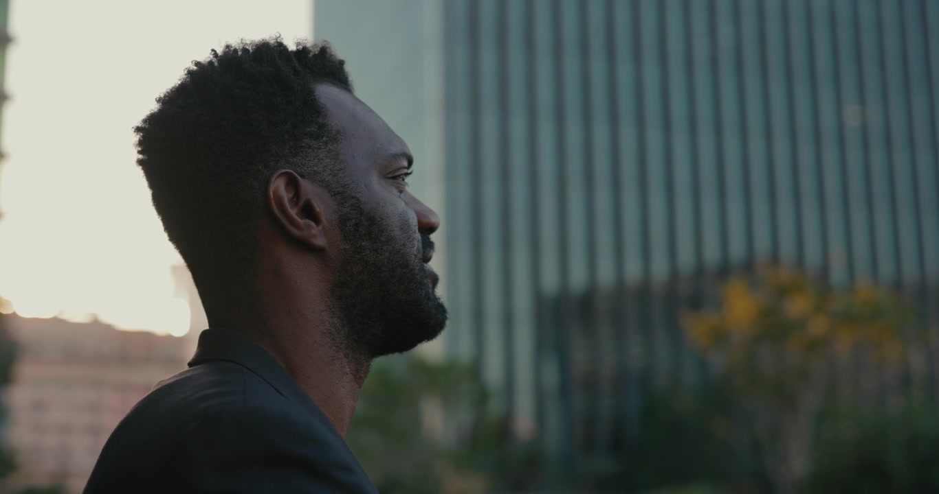 Thoughtful Businessman Looking at City Skyline at Sunset