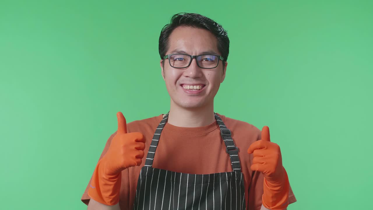 초록색 스크린 스튜디오에 서서 엄지손가락을 올리며 미소 짓는 아시안 남성 집주인의 클로즈업