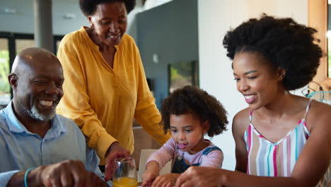 Familienaufnahme-Mit-Großeltern,-Mutter-Und-Enkelin,-Die-Zu-Hause-Am-Tisch-Frühstücken