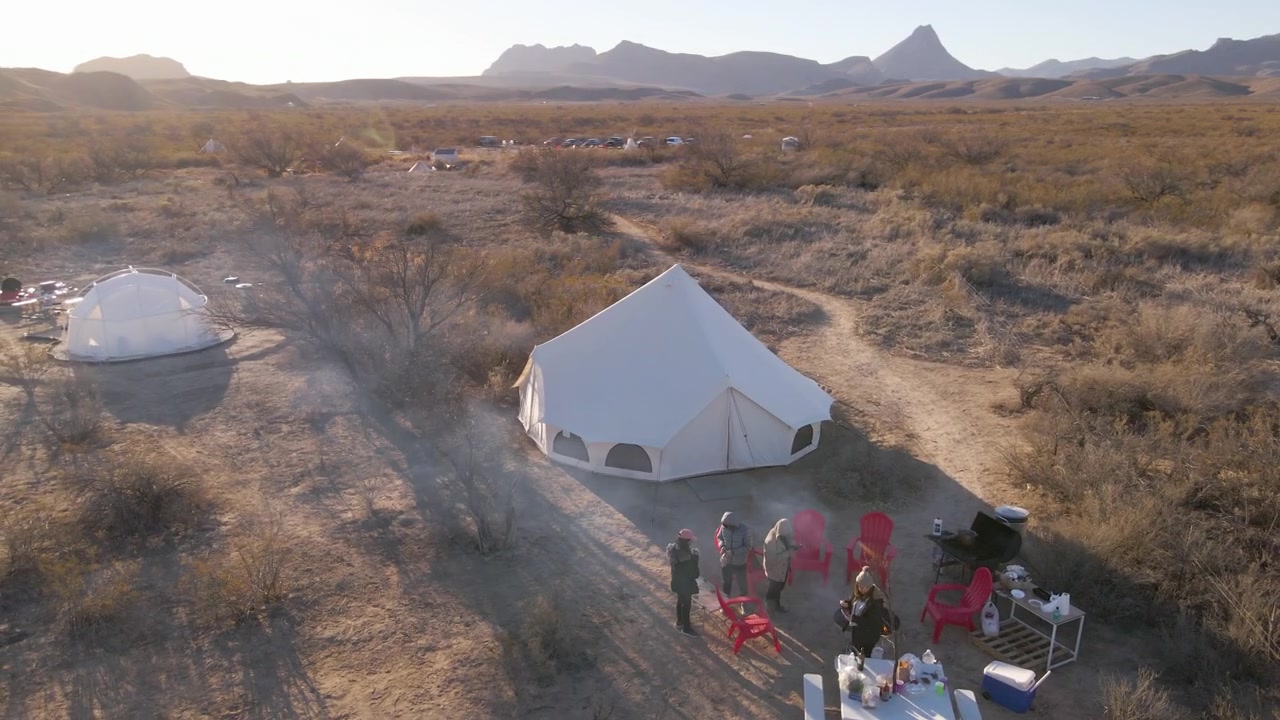 Aerial orbit around campers at yurt site in open desert with campfire. Camping Site in the desert in Big Bend National Park