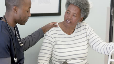 Médico-Afroamericano-Usando-Tableta-Y-Hablando-Con-Una-Mujer-Mayor-En-El-Hospital,-Cámara-Lenta