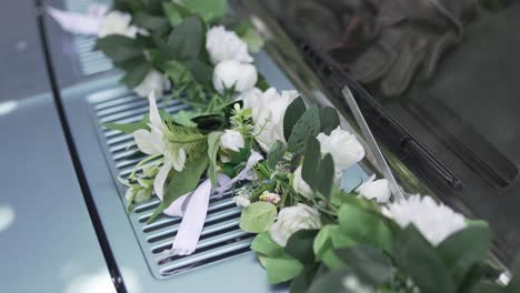 wedding car adorned with white flowers and green leaves, creating a romantic and elegant ambiance