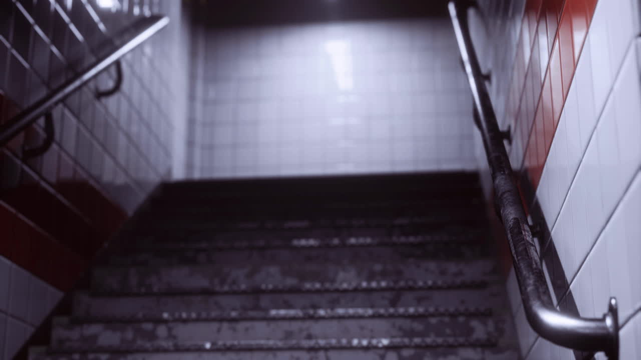 Descent into dimly lit stairway with textured tiles and handrail