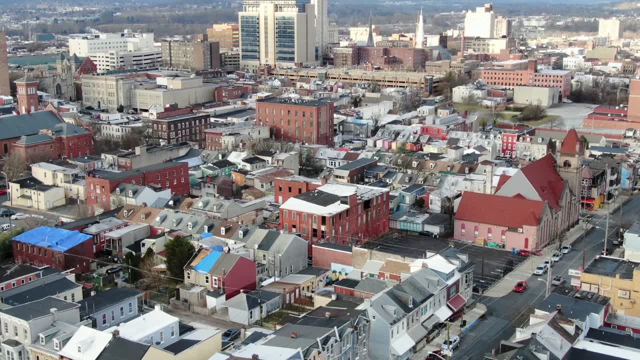 City housing, urban street corner establishing shot, intersection, tight aerial drone shot tilting up to reveal downtown business district and skyscraper office buildings in Reading, Pennsylvania, USA