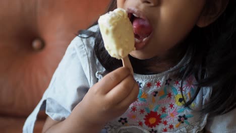 una joven comiendo una barra de helado cubierta de chocolate