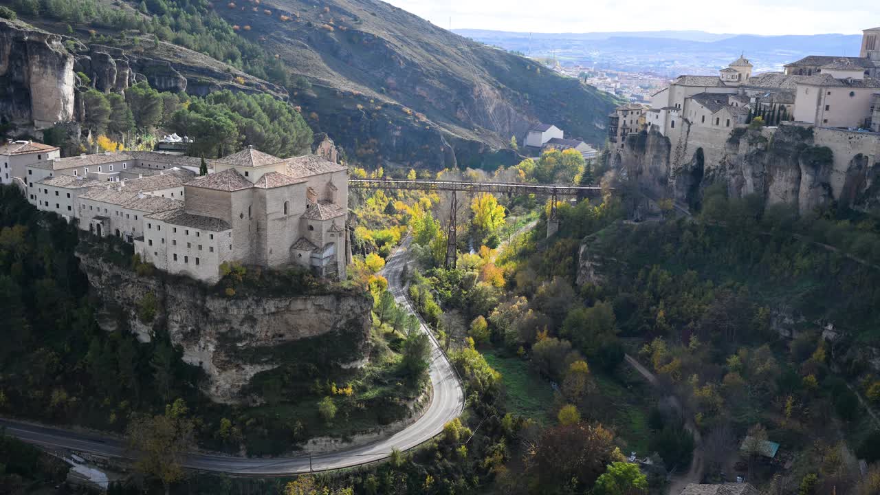 The deep Huecar gorge in Cuenca, Spain, is flanked by historic landmarks, with the former Convent of San Pablo on one side and the Hanging Houses on the other.