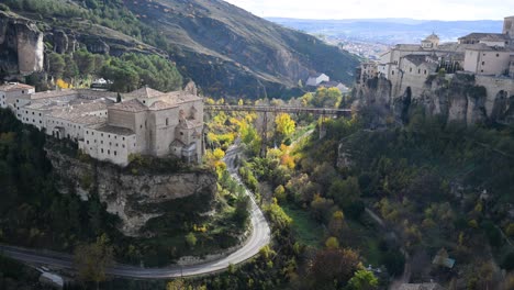 the deep huecar gorge in cuenca, spain, is flanked by historic landmarks, with the former convent of san pablo on one side and the hanging houses on the other.