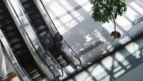 hombres de negocios en una escalera mecánica en un edificio moderno