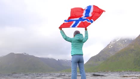 woman with a waving flag of norway on the background of nature