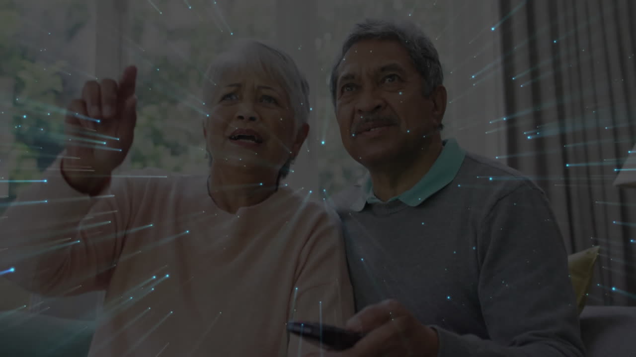 Coppia anziana che guarda la televisione con sovrapposizione di animazione di scie luminose digitali