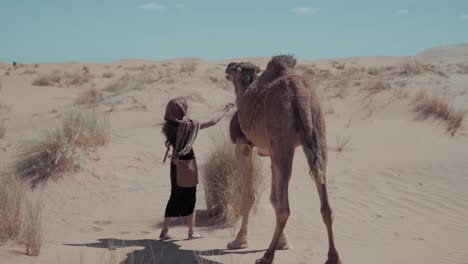 Filmisches-Zeitlupenvideo-Einer-Jungen-Und-Kleinen-Frau,-Die-Ein-Kamel-Streichelt,-Nachdem-Sie-Viele-Stunden-Lang-Durch-Die-Sahara-Zu-Ihrem-Ziel-In-Marokko-Geritten-Ist