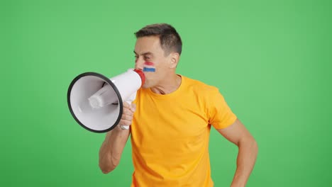 Excited man with dutch flag on face using a megaphone