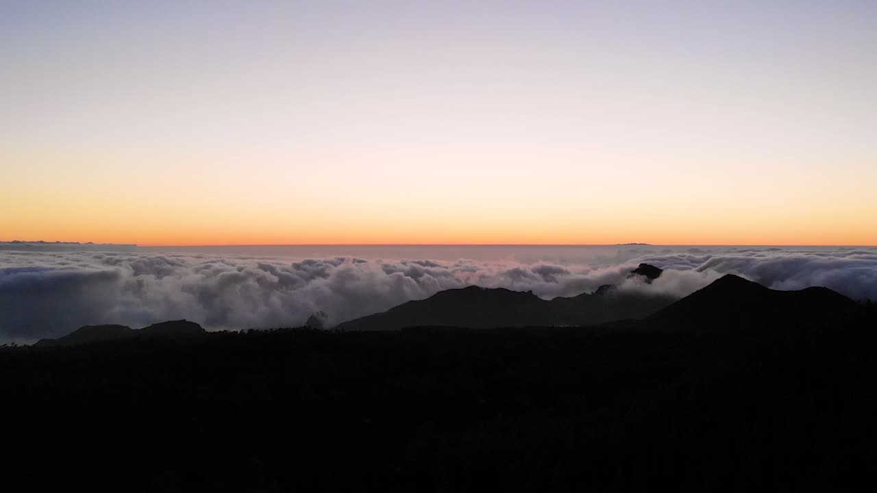 A beautiful sunset at Teida Mountain in Tenerife. An aerial view after the sun has settled down with the clouds under us. The sky is still golden while the land has become dark.