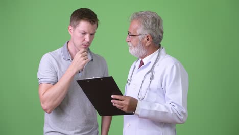 anciano barbudo médico consultando hombre paciente contra fondo verde