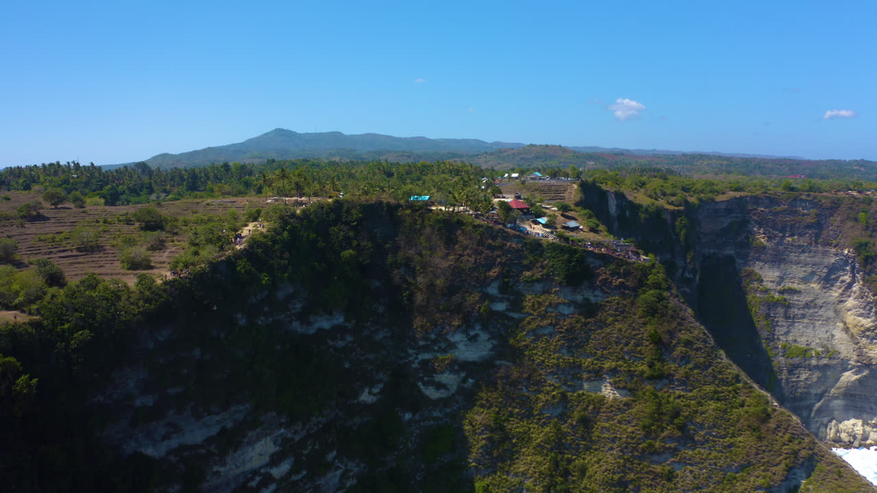 playa kelingking, nusa penida en bali indonesia filmando acantilado desde donde los turistas toman fotos