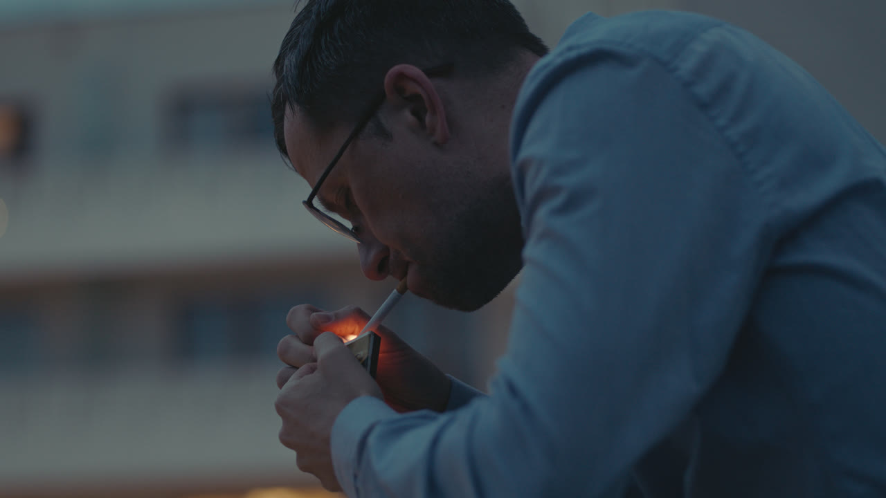 Um homem triste de camisa fuma um cigarro na varanda.