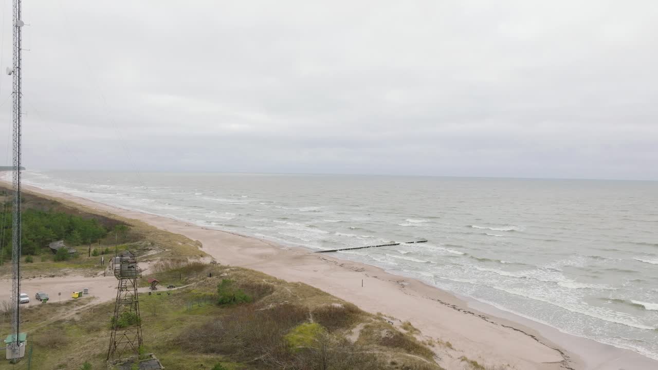 пасмурный день, старый деревянный пирс, белый песчаный пляж, большие штормовые волны бьются о берег, изменения климата, широкая съемка с беспилотника, движущийся вперед высокий