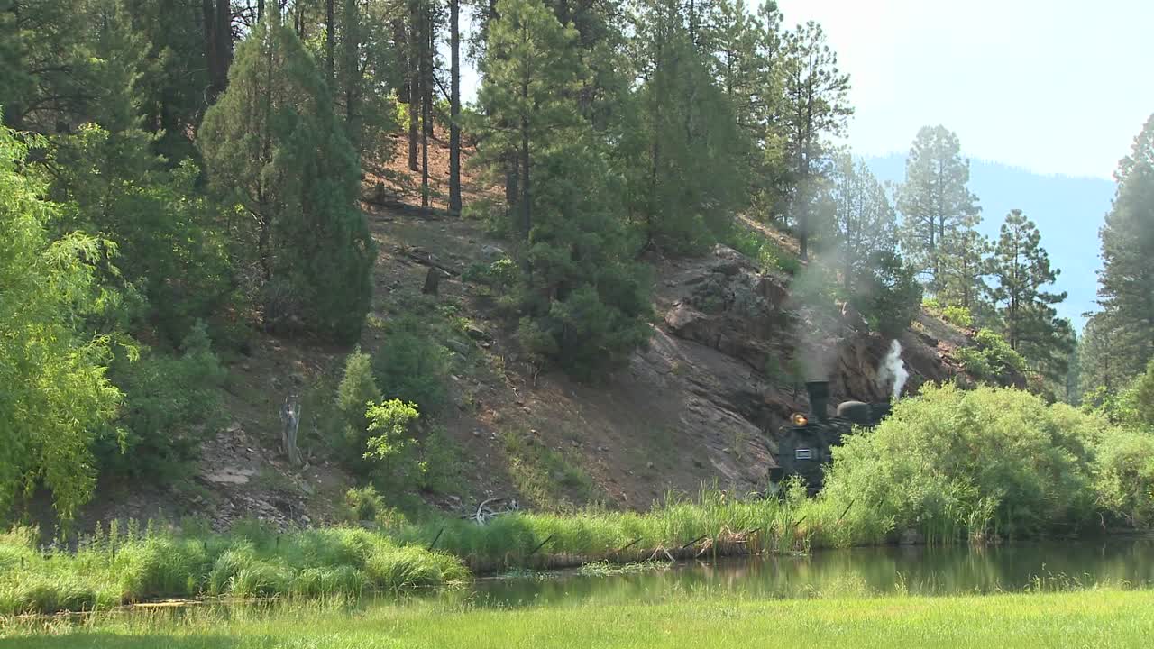 un tren de vapor se mueve alrededor de una curva en las montañas rocosas 1