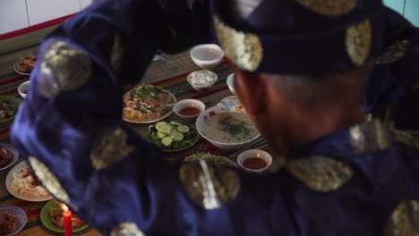 Over-the-shoulder-shot-of-religious-old-Asian-man-offering-table-of-holy-food-god