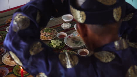 over the shoulder shot of religious old asian man offering table of holy food god