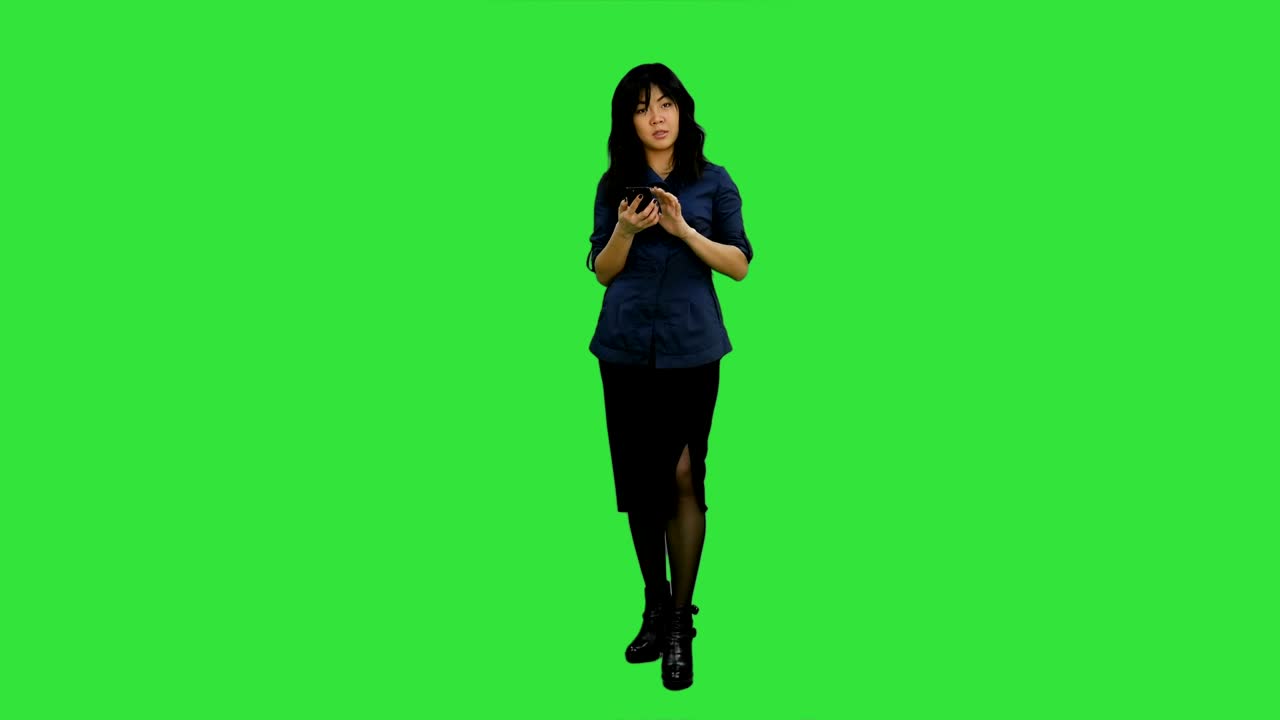 Giovani donne asiatiche in piedi con smartphone e che parlano a una telecamera su schermo verde, Chroma Key