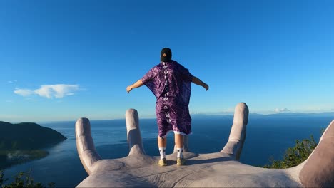 hombre parado en una palma gigante hecha por el hombre con un cartel de "buscar incomodidad" con vistas panorámicas al océano en el monte caningag, pintuyan, leyte del sur, filipinas