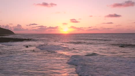 Atemberaubender-Sonnenuntergang-Am-Meer-Mit-Wellen,-Intensiv-Gelber-Sonne,-Rosafarbenem-Himmel-Und-Orangefarbenem-Horizont