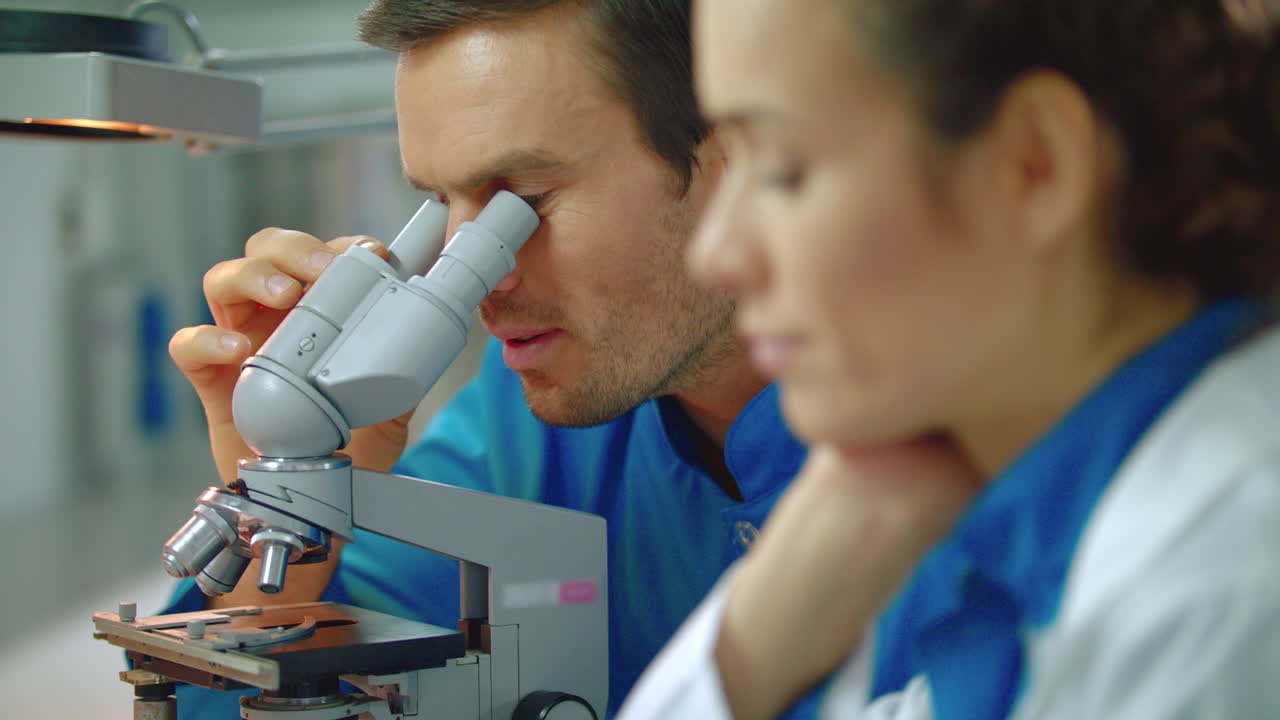 Scientist team working in laboratory. Close up of doctors team using microscope