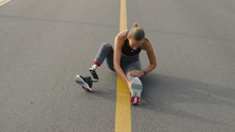 mujer discapacitada estirando las piernas en la superficie de carrera. deportista haciendo ejercicio en el parque