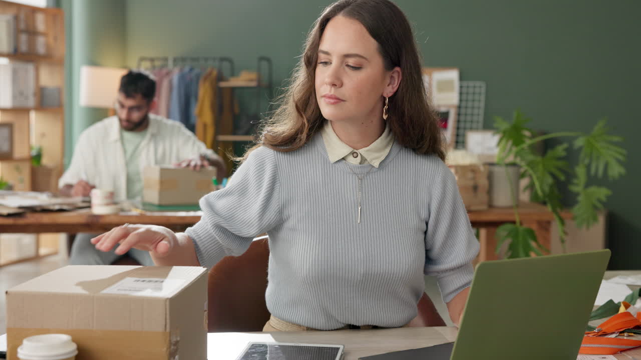 Donna che imballa ordini per la spedizione con un laptop in ufficio