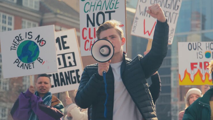 Gruppo di manifestanti con cartelli e megafono in una marcia di protesta contro il cambiamento climatico.
