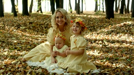 beautiful young woman with maple leaves sitting with her baby